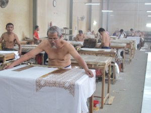 This man is carefully preparing for cap printing a different design, areas have to be masked out with waxed paper.