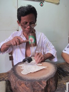Using small chisels made from spokes of a motorbike wheel to carve the tiny symbols.