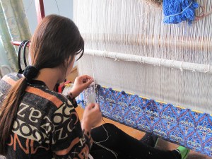 Lady working on a traditional design on silk carpet made with naturally dyed silk threads.